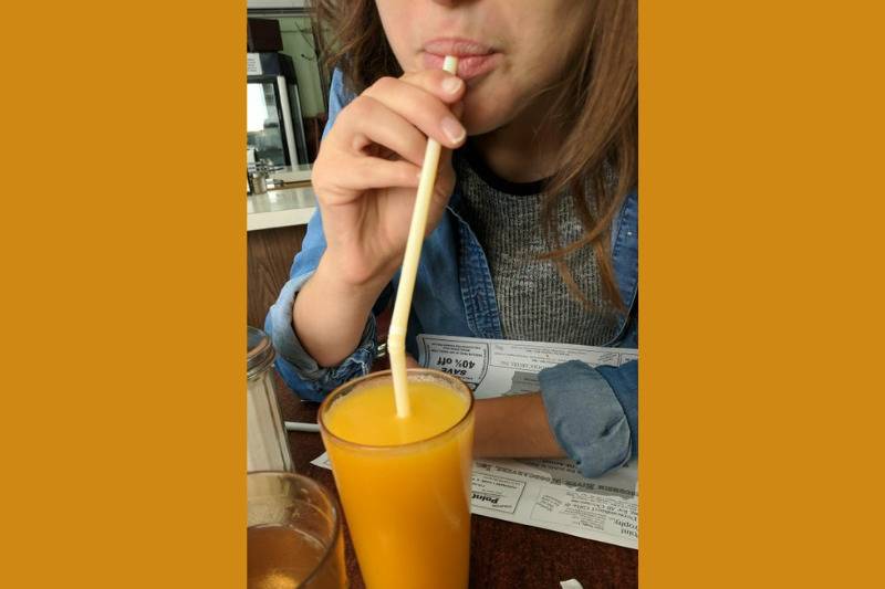 girl using a straw upside down to drink juice