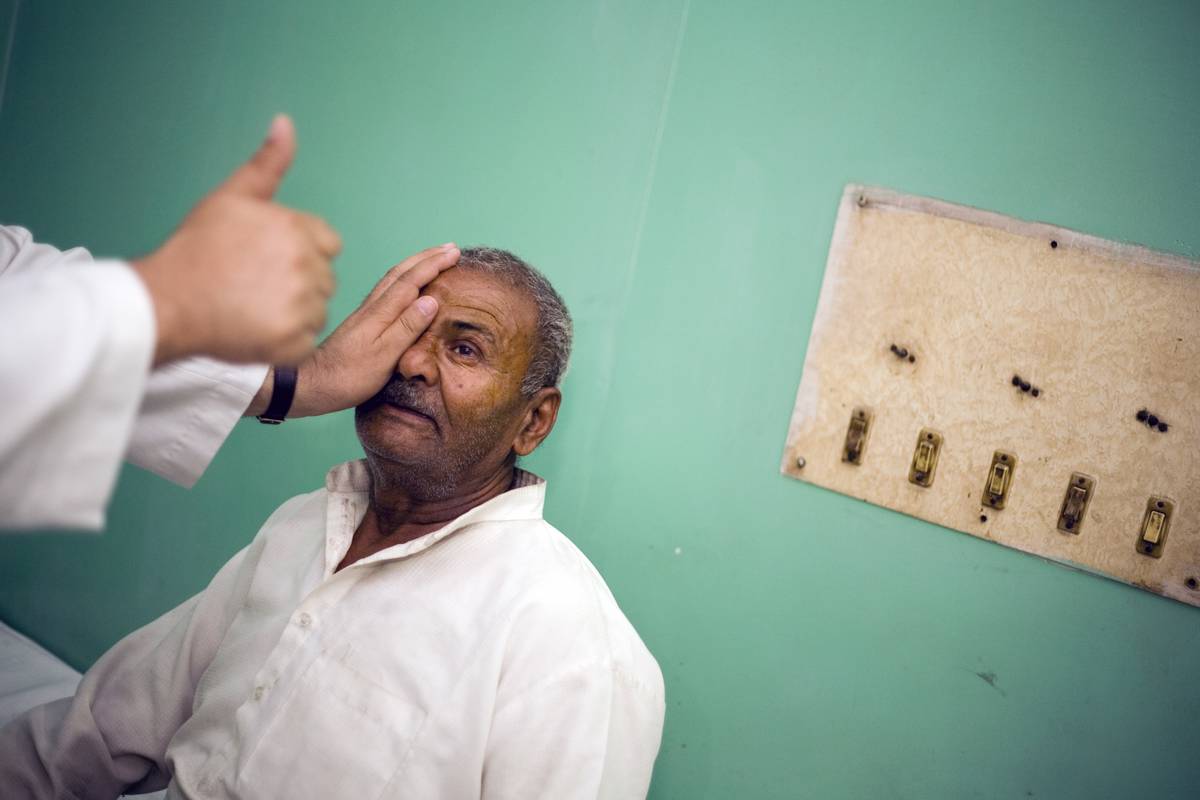 A doctor covers a patient's eye during a vision test.