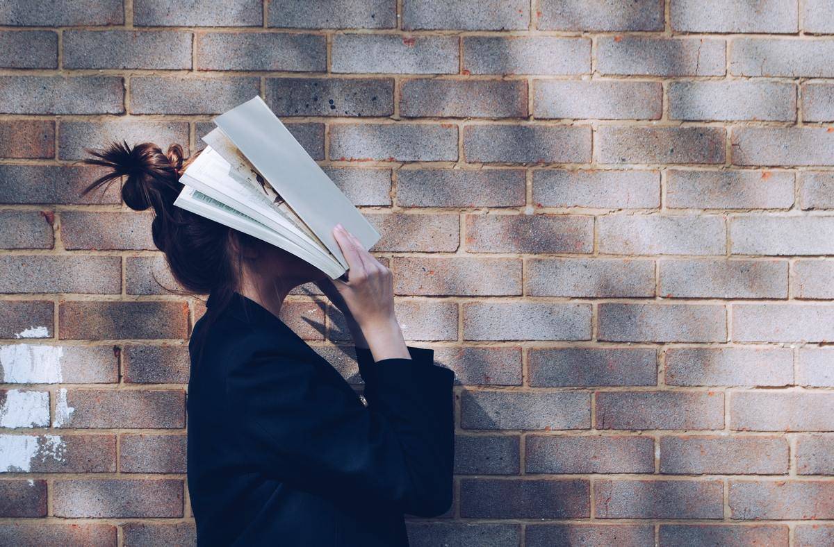 woman holds textbook over her head