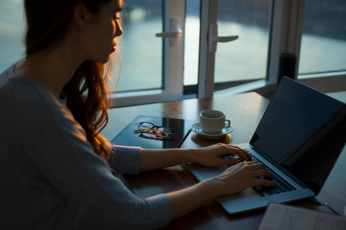 woman typing on laptop by window door