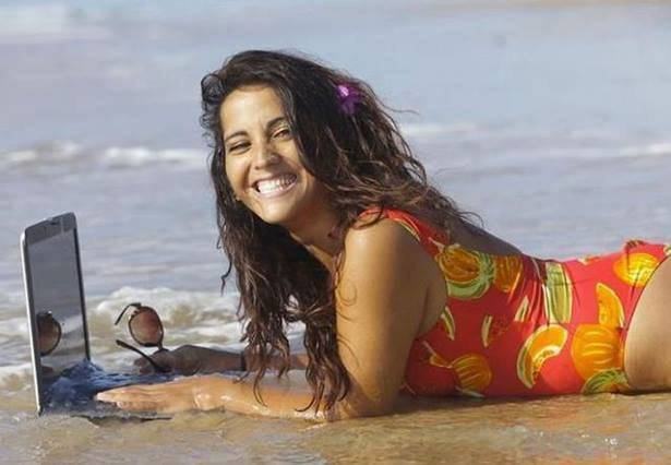 woman lying on beach with laptop in the water