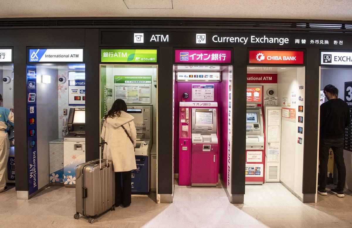 A woman gets cash at an airport ATM in Tokyo.