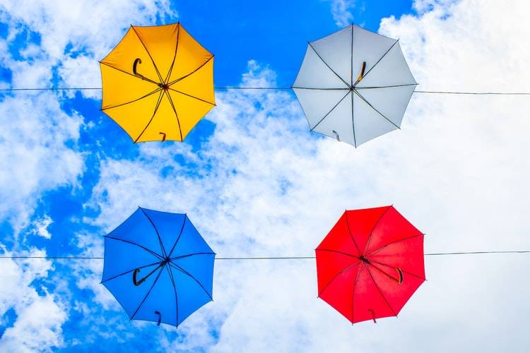 Four umbrellas floating in the sky in a square formation