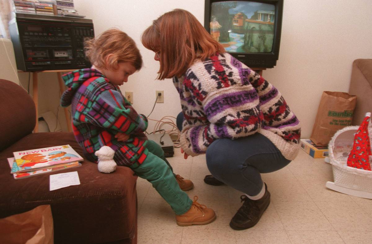 small girl having a temper tantrum woman bent down in front of her trying to talk
