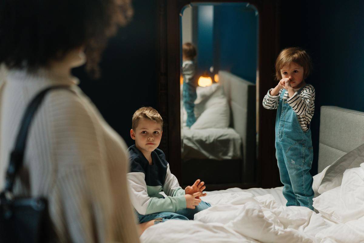 babysitter walking into bedroom to find two children standing on the bed