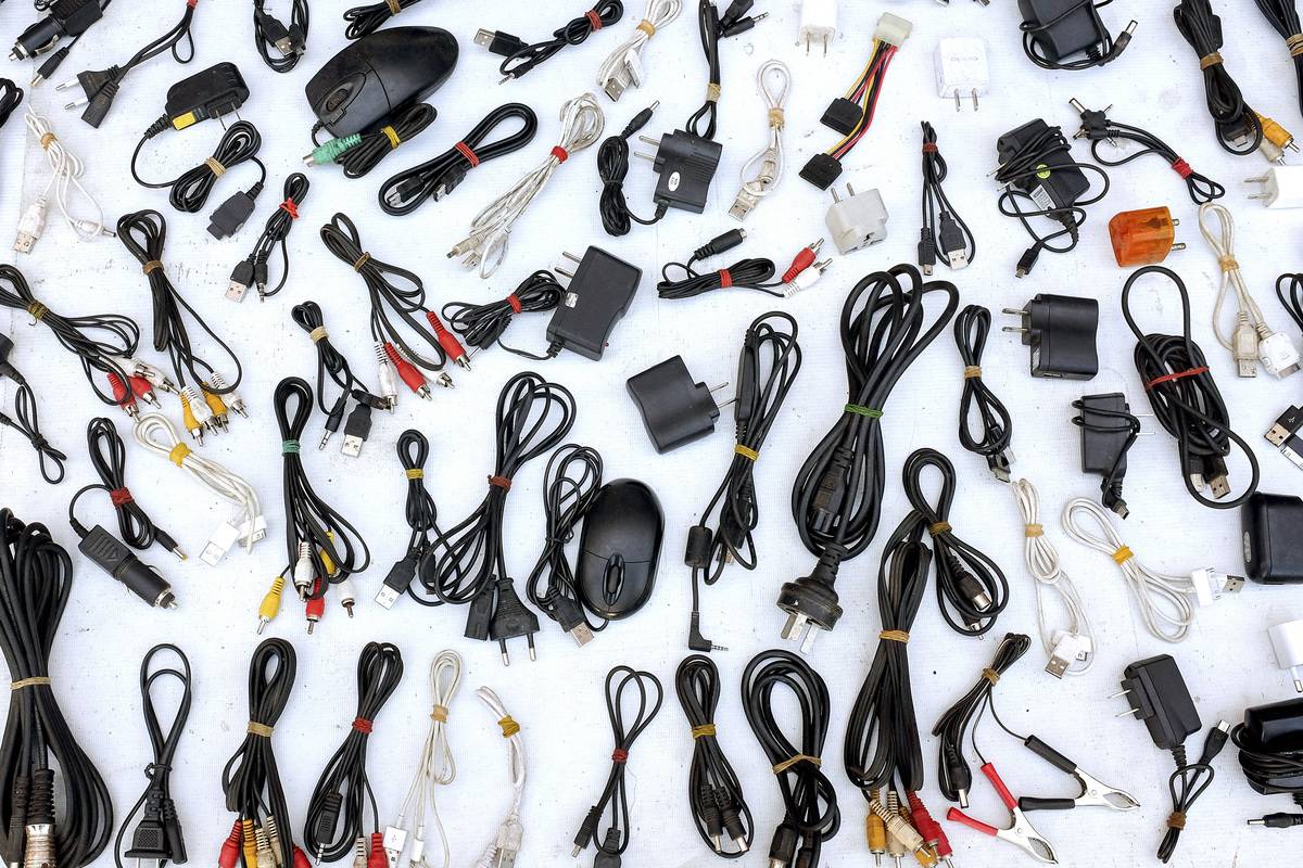 A myriad of phone chargers lie on a white table.