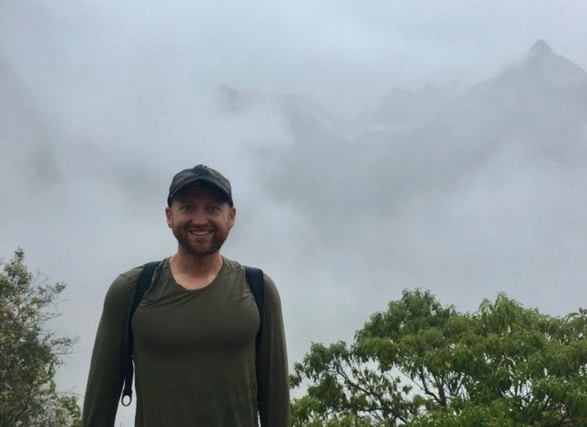 guy at top of mountain and the view is very cloudy 