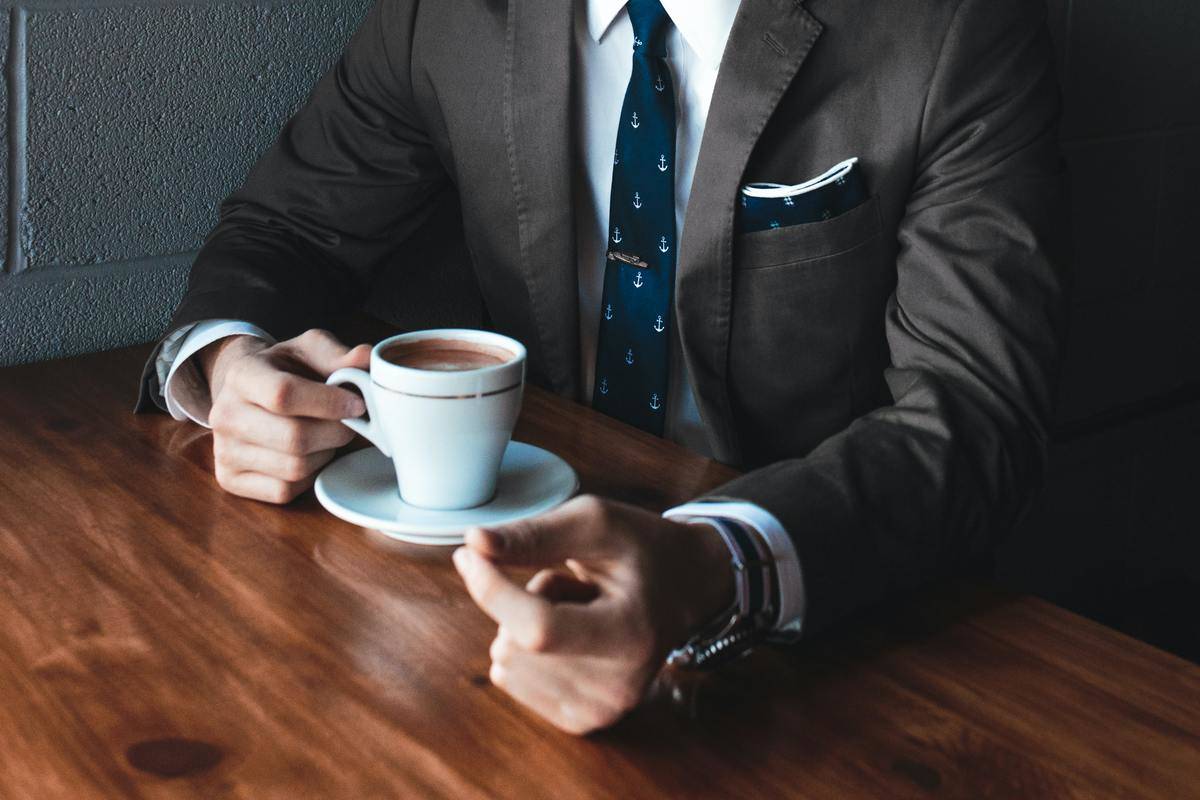 man in suit drinking coffee at desk