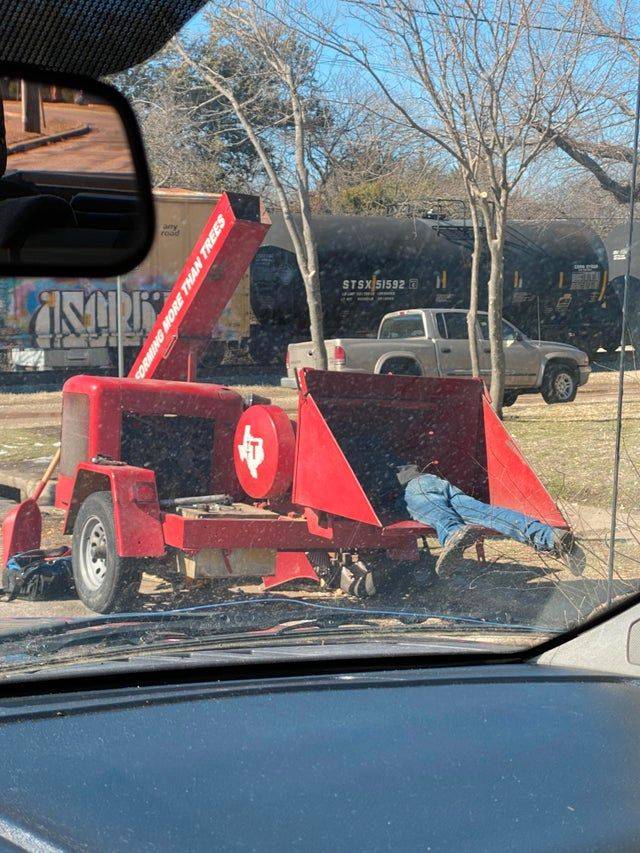 man grabbing something out of woodchipper
