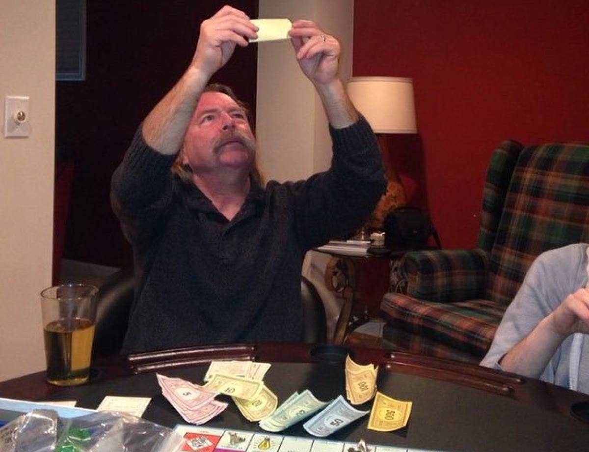 guy holding a monopoly bill above his head to see if it is counterfeit 