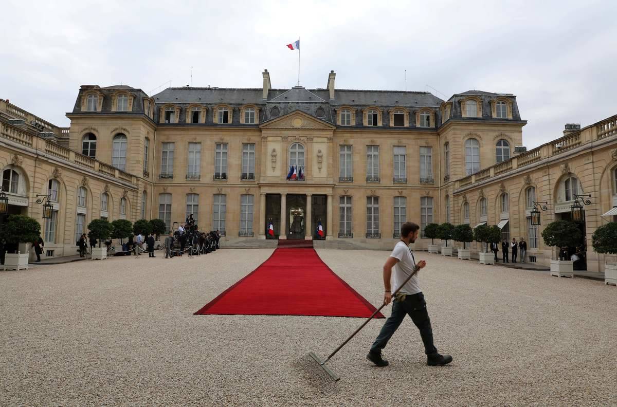 An Elysee Palace employee rakes the pebbles on which the red carpet has been rolled out, before the arrival of the Lebanese president to the Elysee Palace