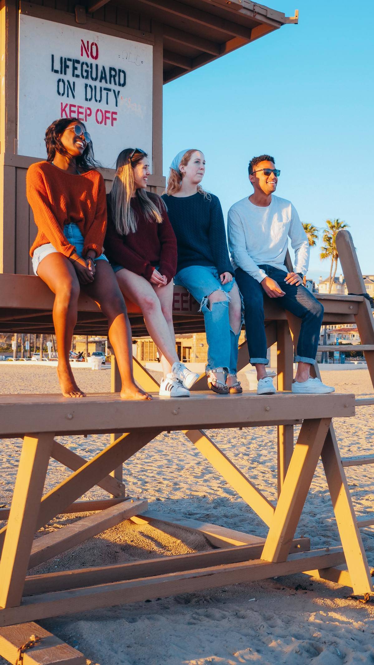 group of three women and one man sitting at the beach