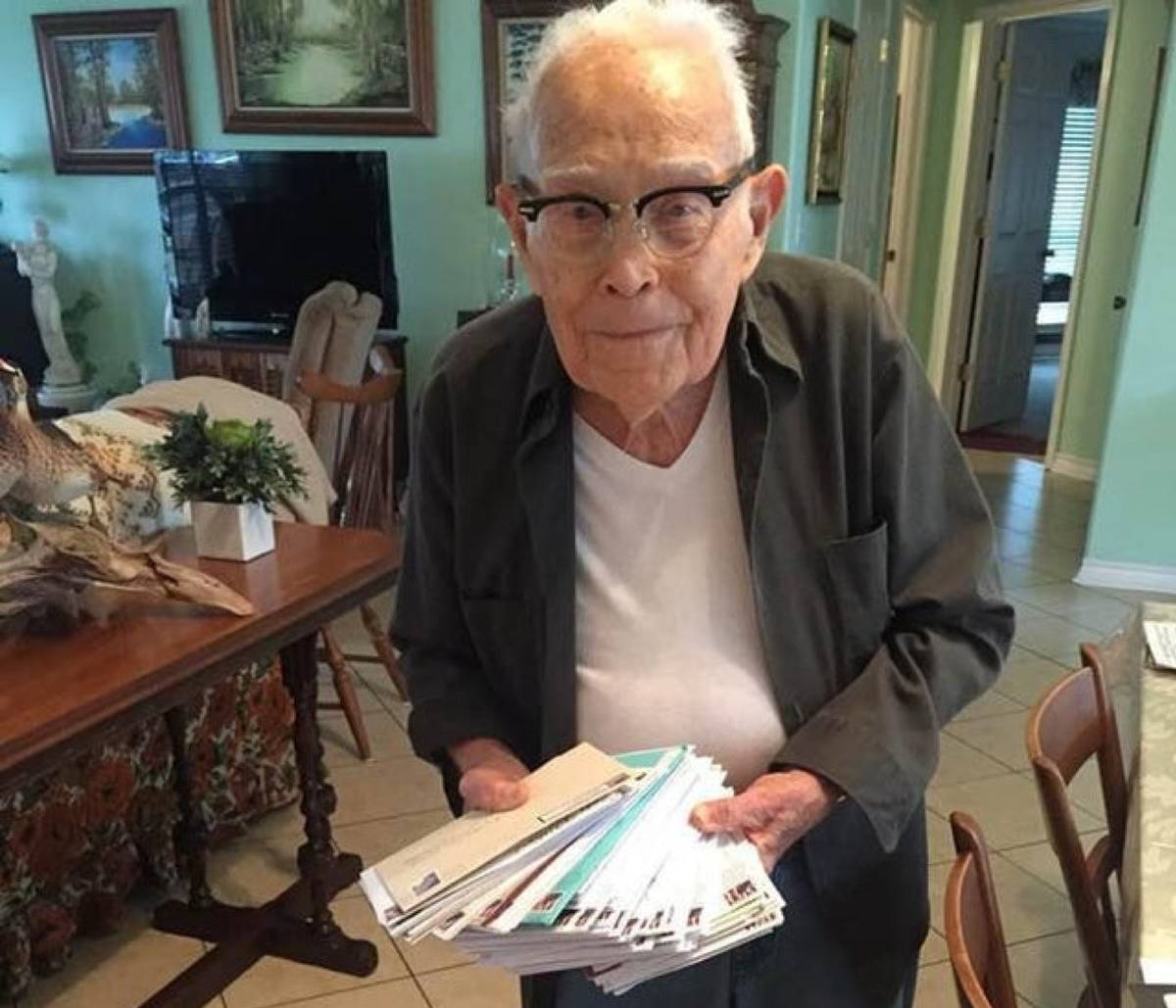happy grandpa smiling at camera with all of his birthday cards in his hands