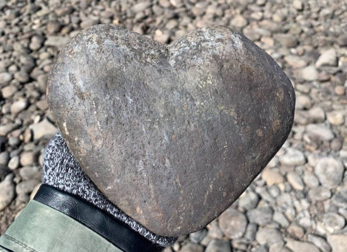 person holding a large, heart shaped rock 