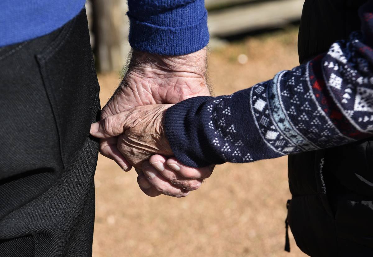 A senior couple walks hand-in-hand.