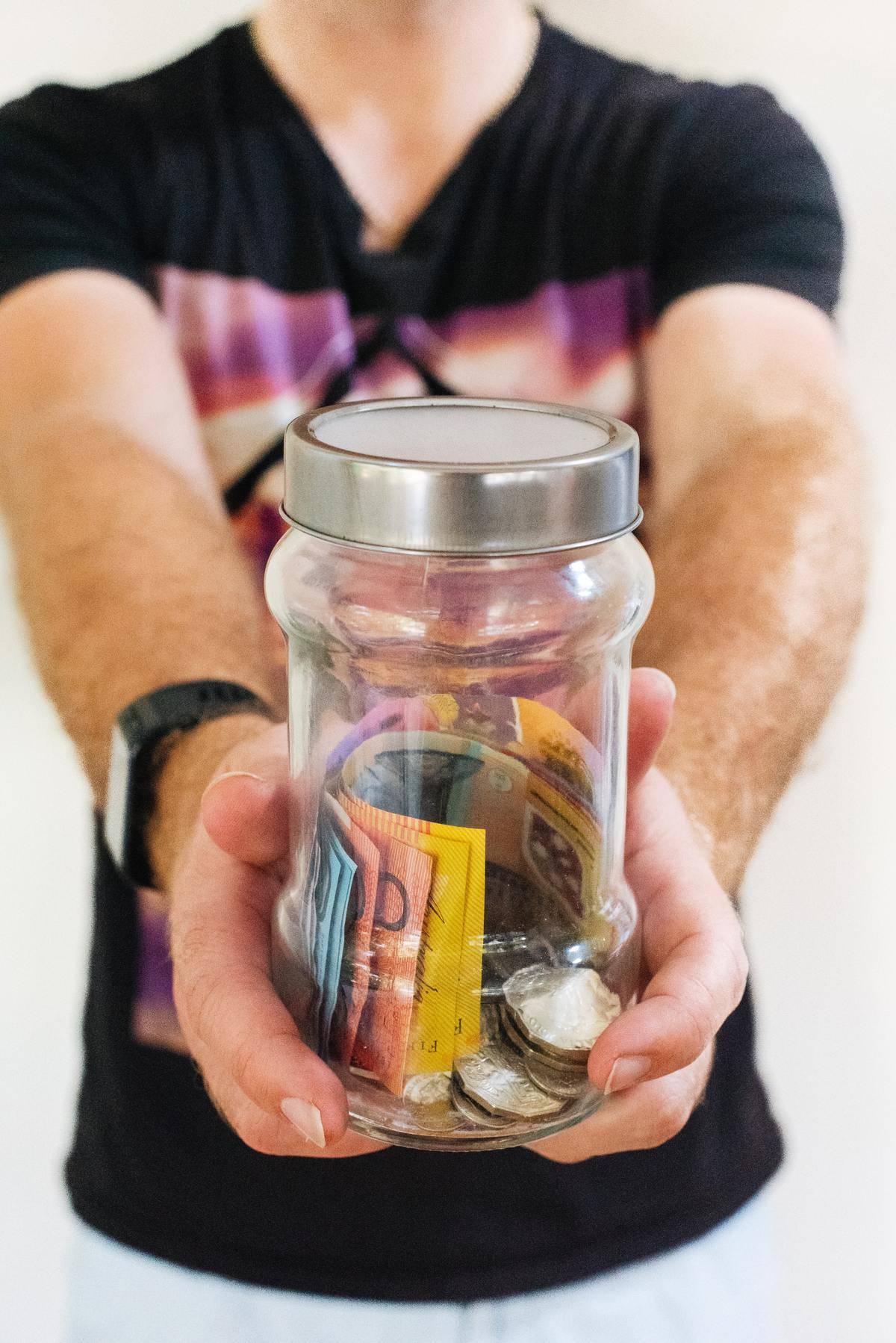 person holding out money in a bottle