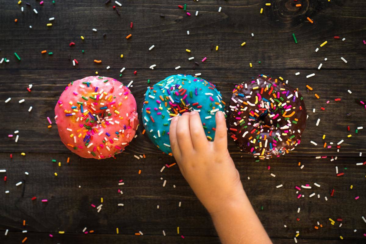 kid's hand grabbing one of three donuts
