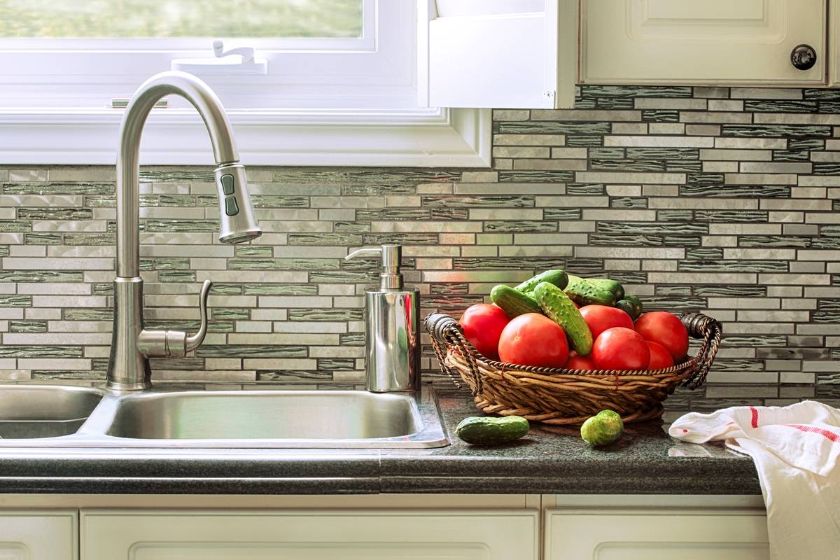 Fresh tomatoes and cucumbers in basket on the kitchen countertop near sink