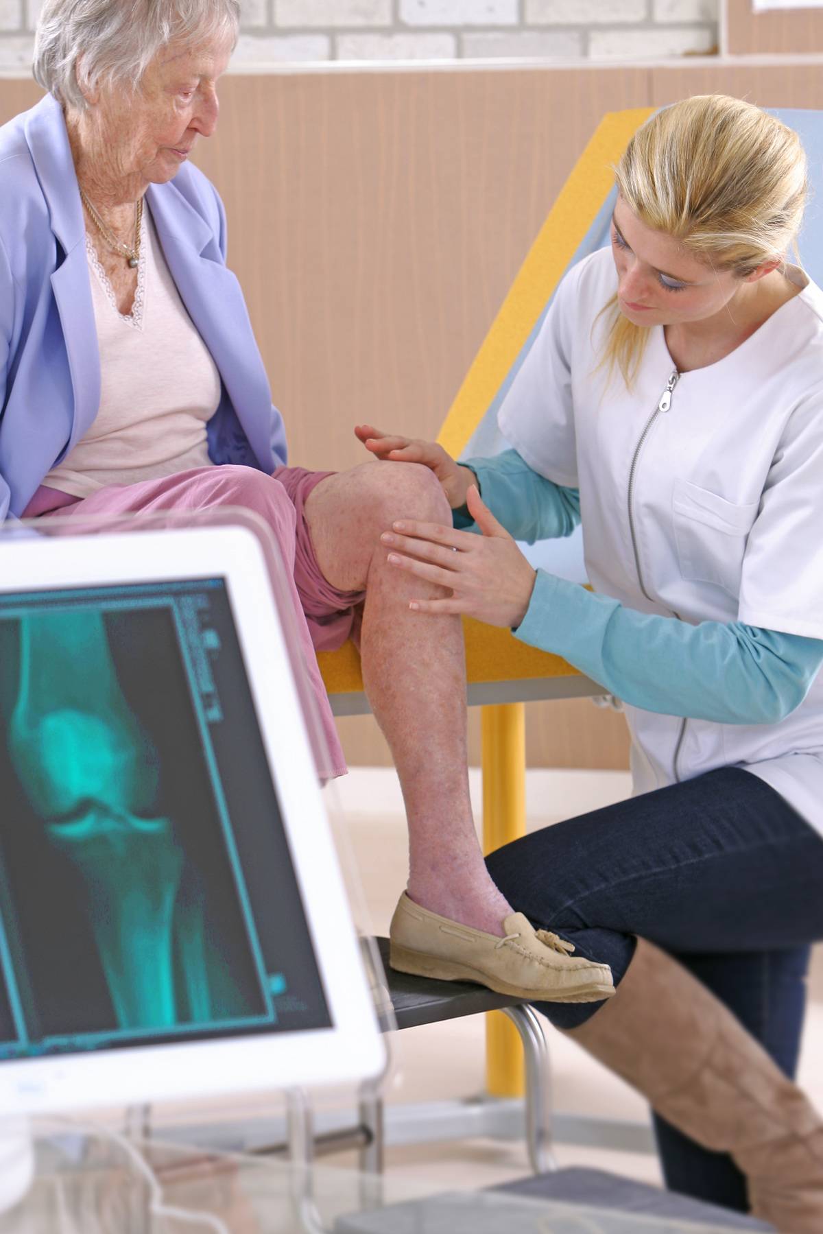 A doctor examines an elderly patient's knee.