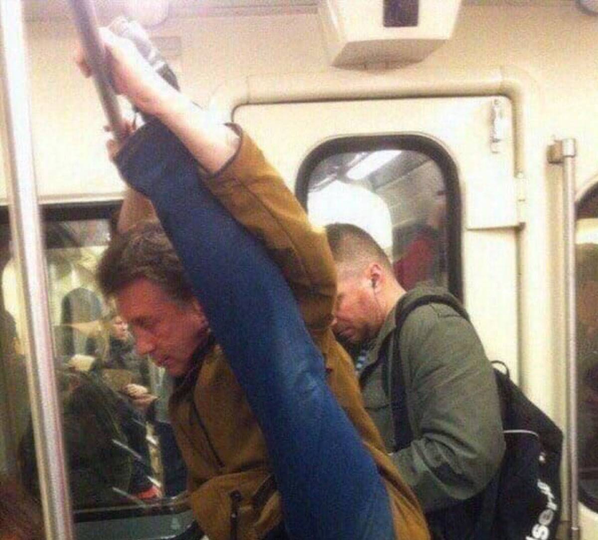 guy stretching his leg on the handlebar in the subway 