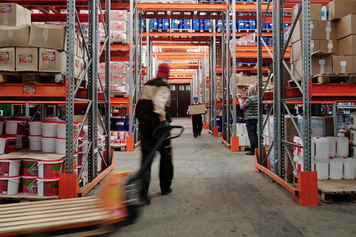 man pulling empty pallet through warehouse