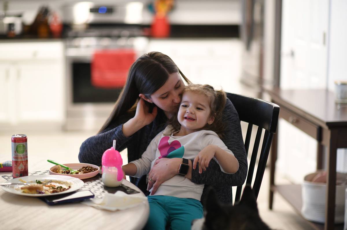 Nina Beck, 30, kiss her daughter Emmie, 2, during dinner at their house in Littleton, Colorado on Tuesday, March 16, 2021.
