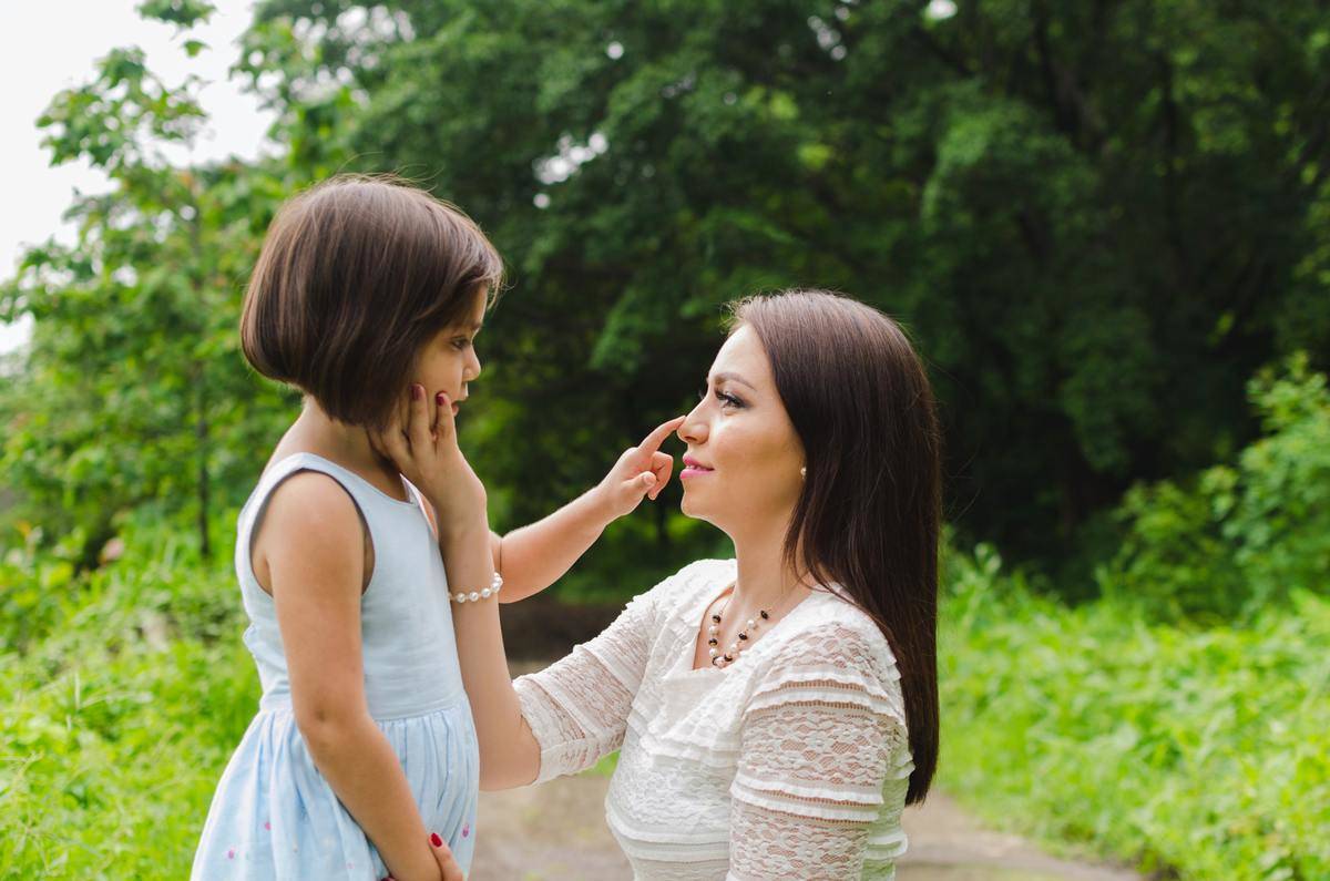 mom bent down talking to daughter standing in front of her
