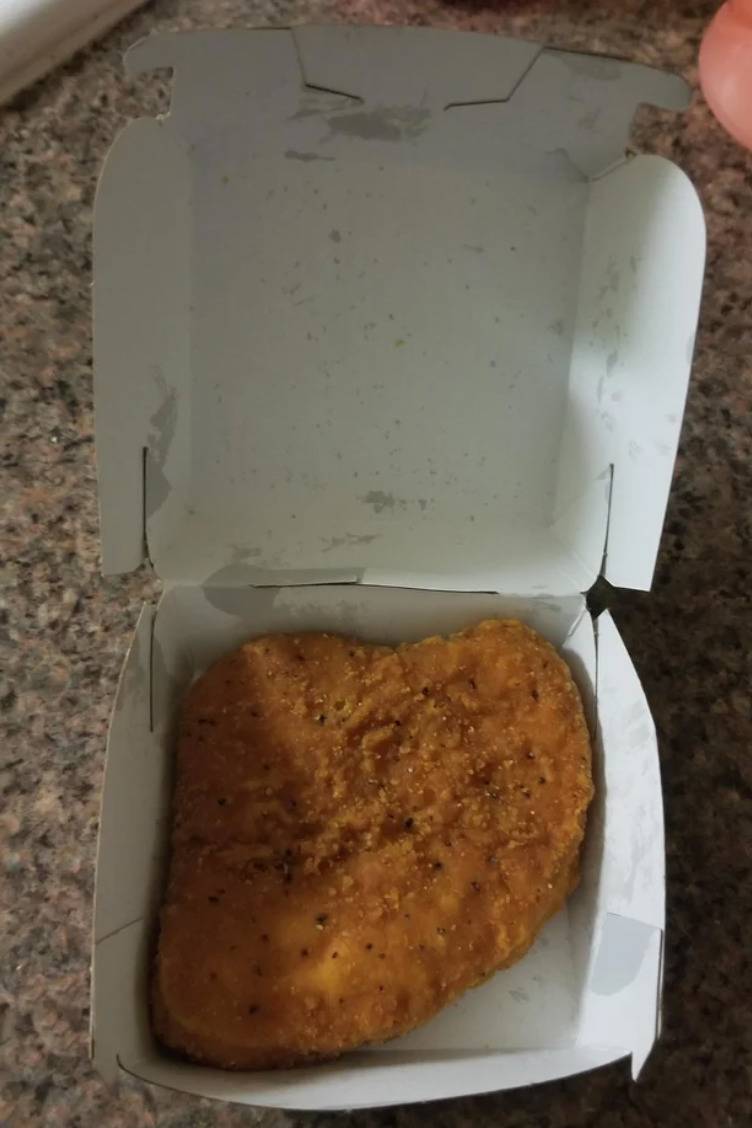 box with a singular large piece of breaded chicken