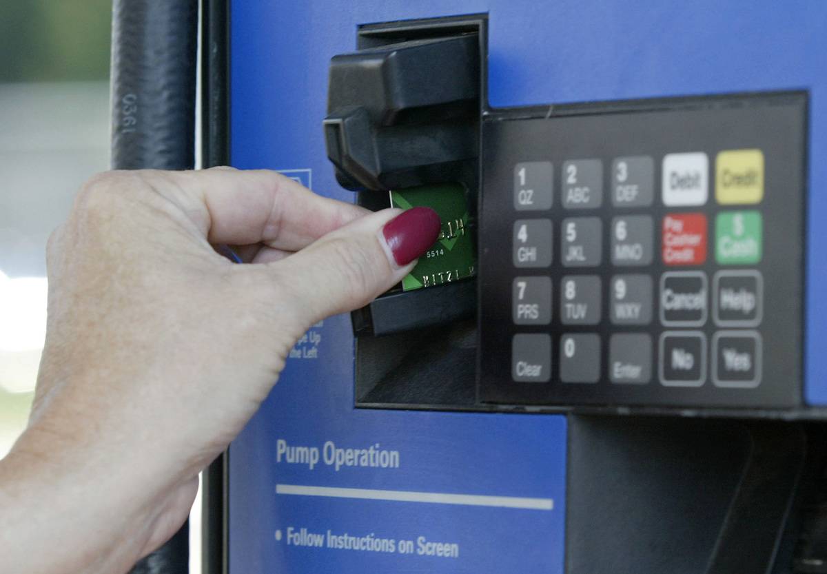 A woman uses a credit card to pay for gas at a station.
