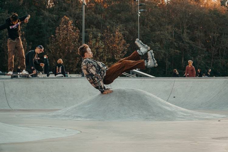 guy doing a trick on rollerblades in the middle of a skate park 