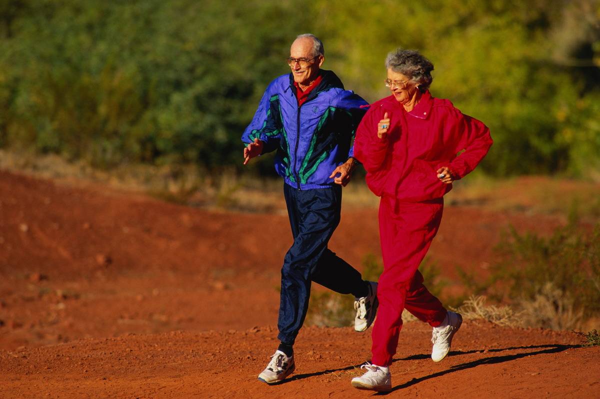 Two elderly adults run together.