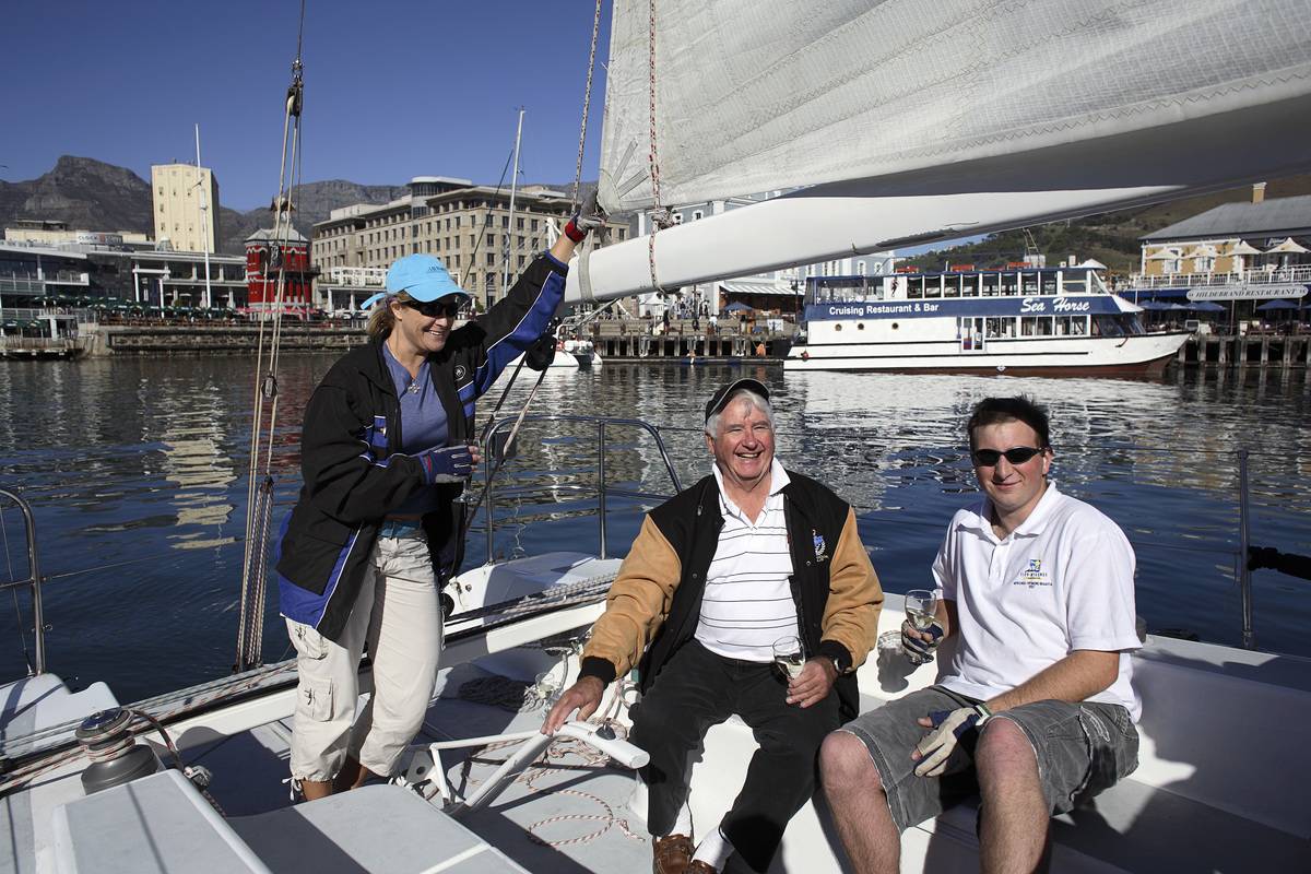 An elderly man and woman sail on a boat through a harbor.