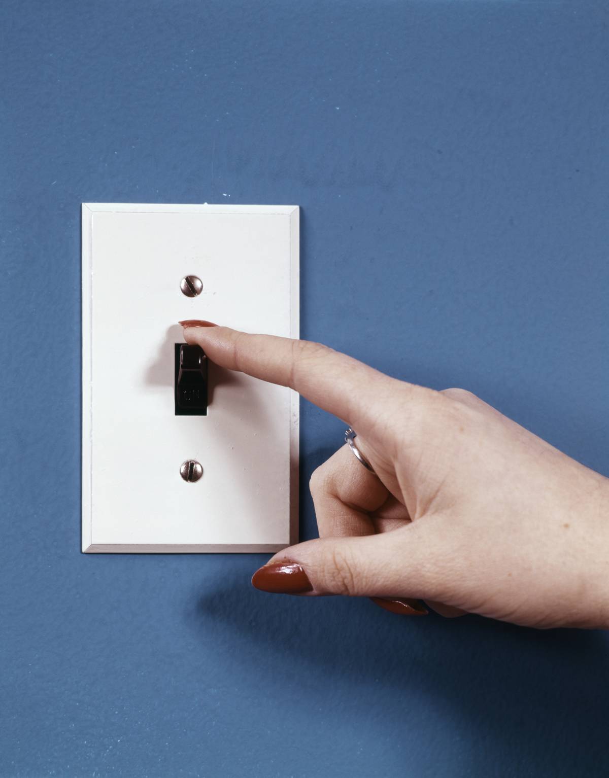 A woman's hand flips the light switch.