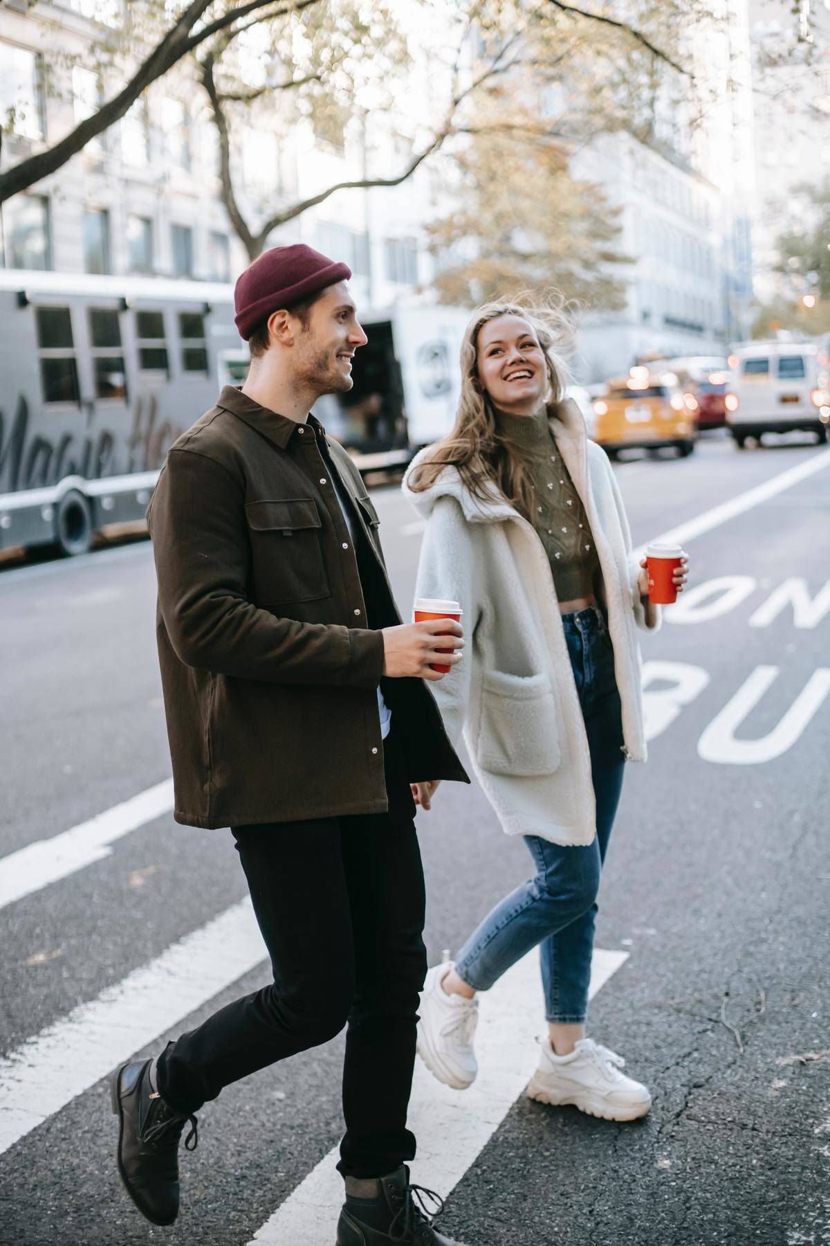 man and woman walking and talking while drinking coffee