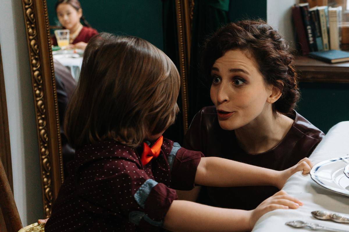 woman squatting down speaking to little girl seated at table