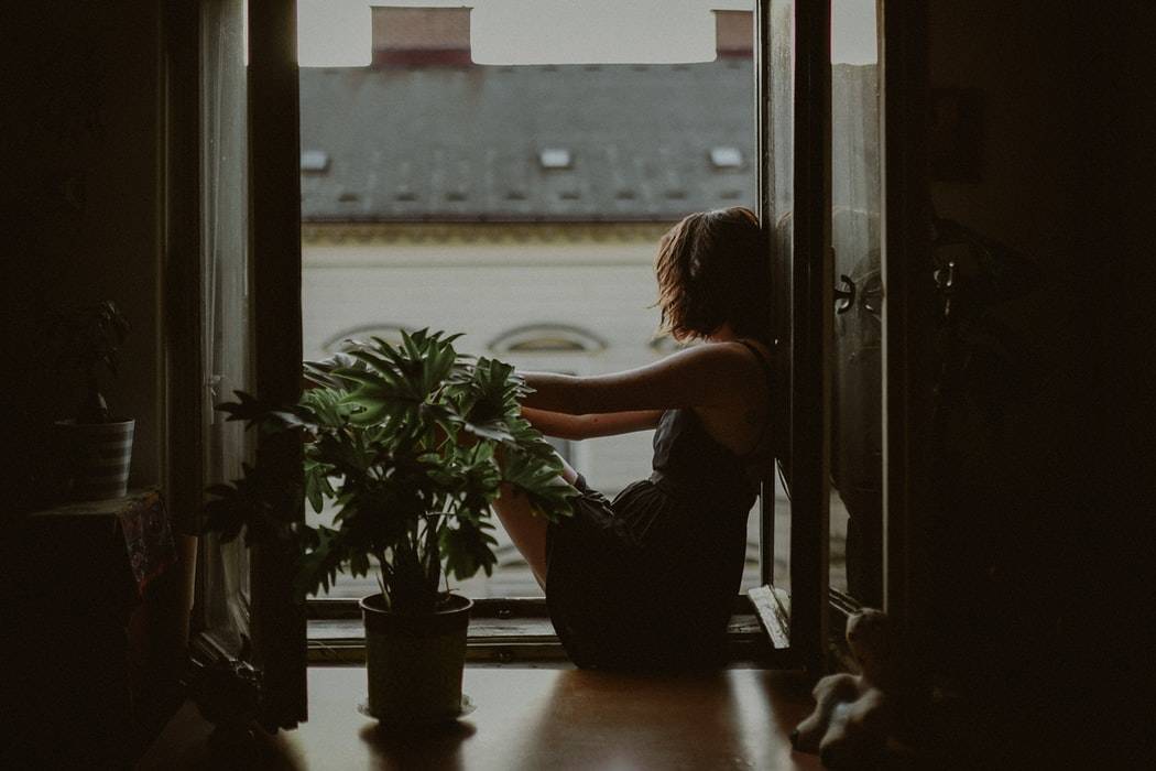 Side shot of woman sitting by window staring out at the view 