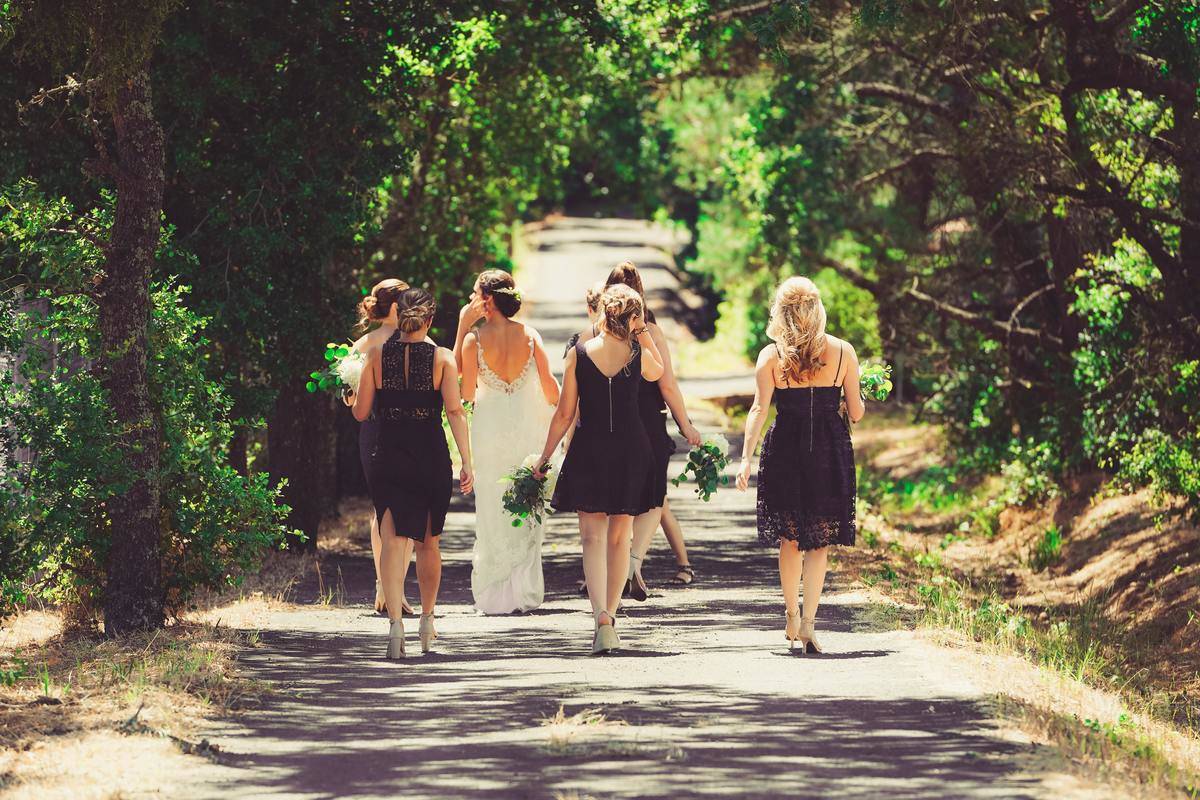 Bride and bridemaids walking into forest park