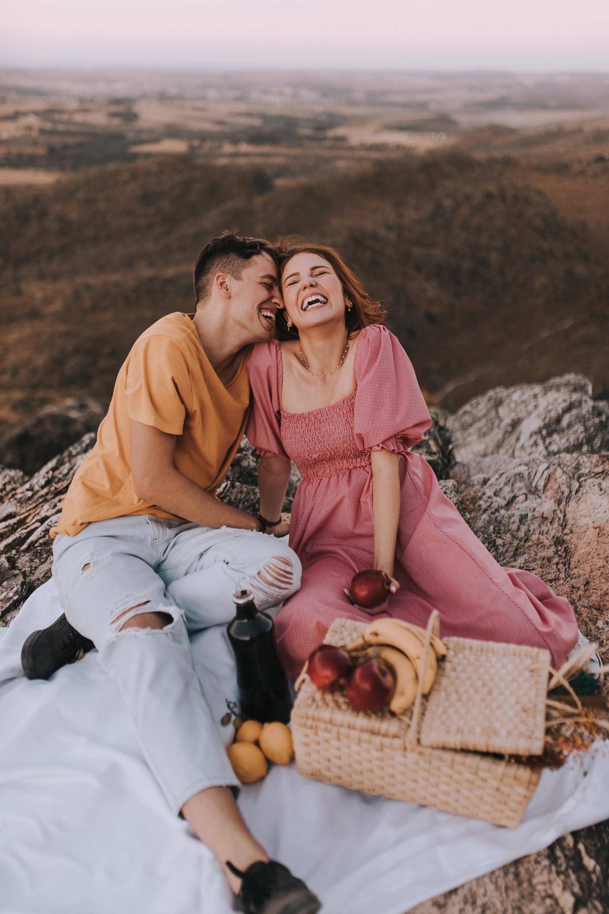 Couple has picnic on cliff by sunset