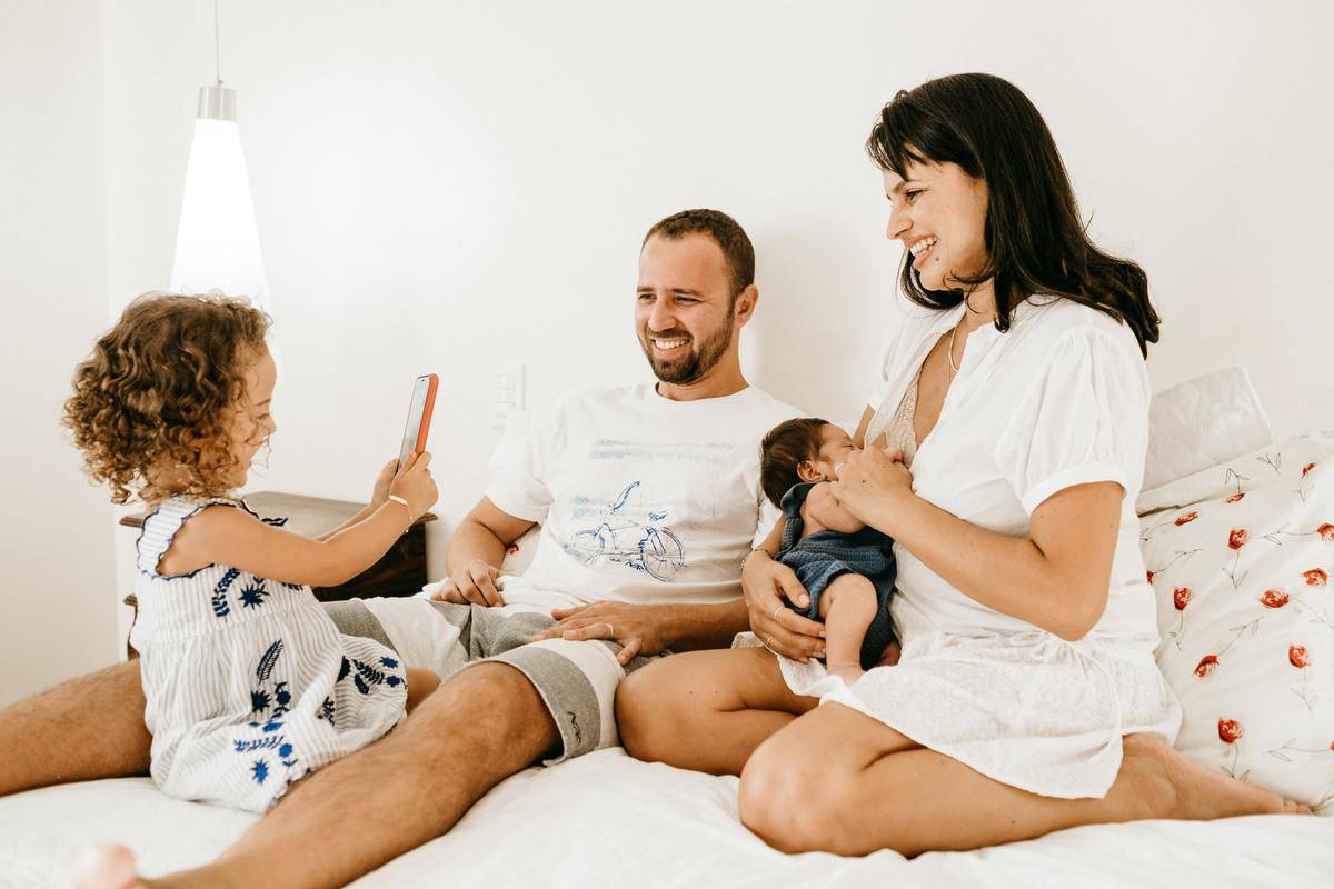 Family smiling while hanging out in bed with kids