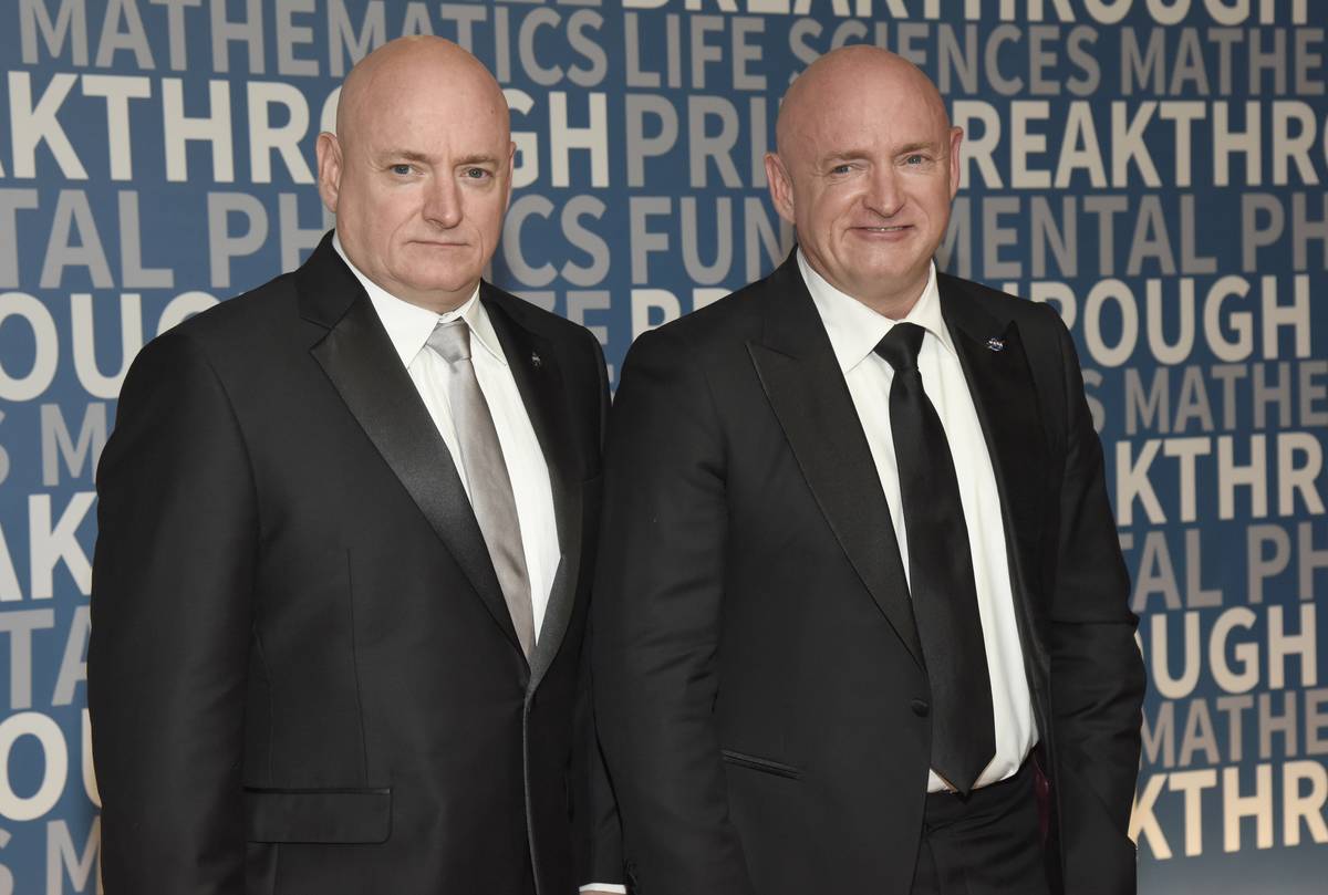 Scott Kelly and Mark Kelly stand together to accept NASA awards.