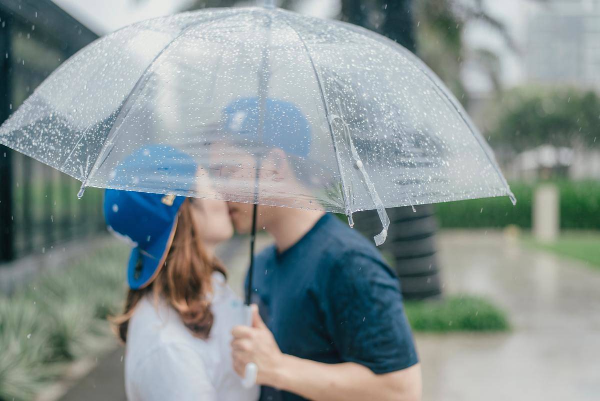 Man and woman kiss under umbrella