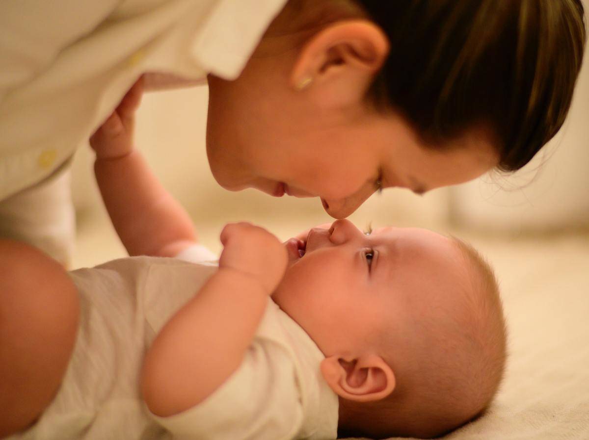 Mom kisses baby looking at her