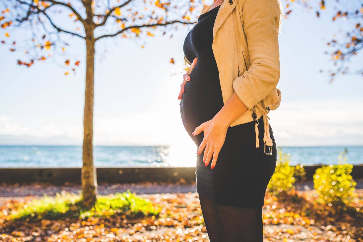 Pregnant woman stands by the water