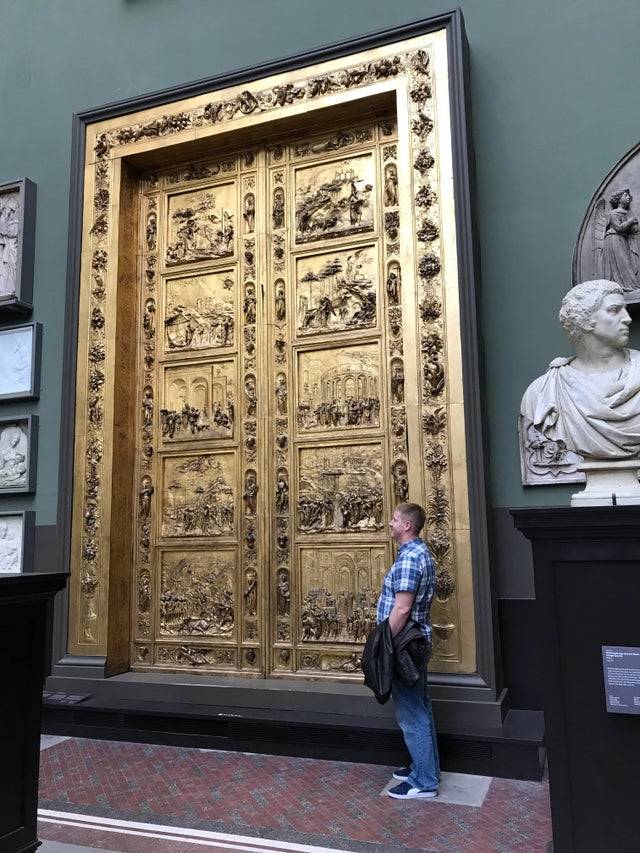 man standing next to large doors at the Victoria & Albert Museum in London