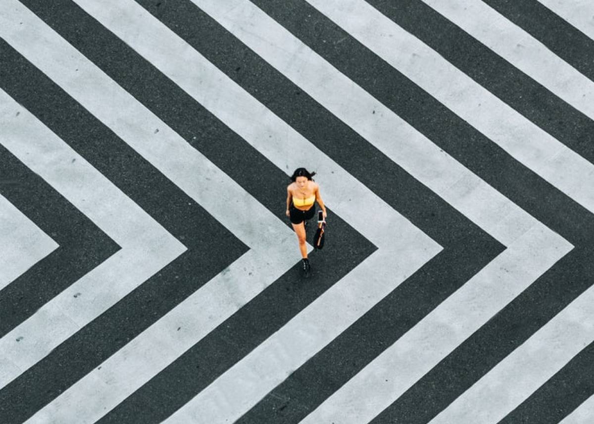 Birds-eye view of woman walking on black and white striped sidewalk 