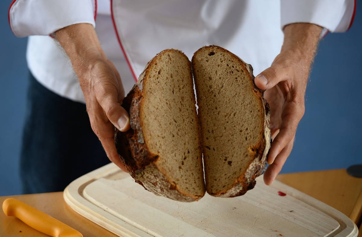 A chef breaks open a loaf of bread.