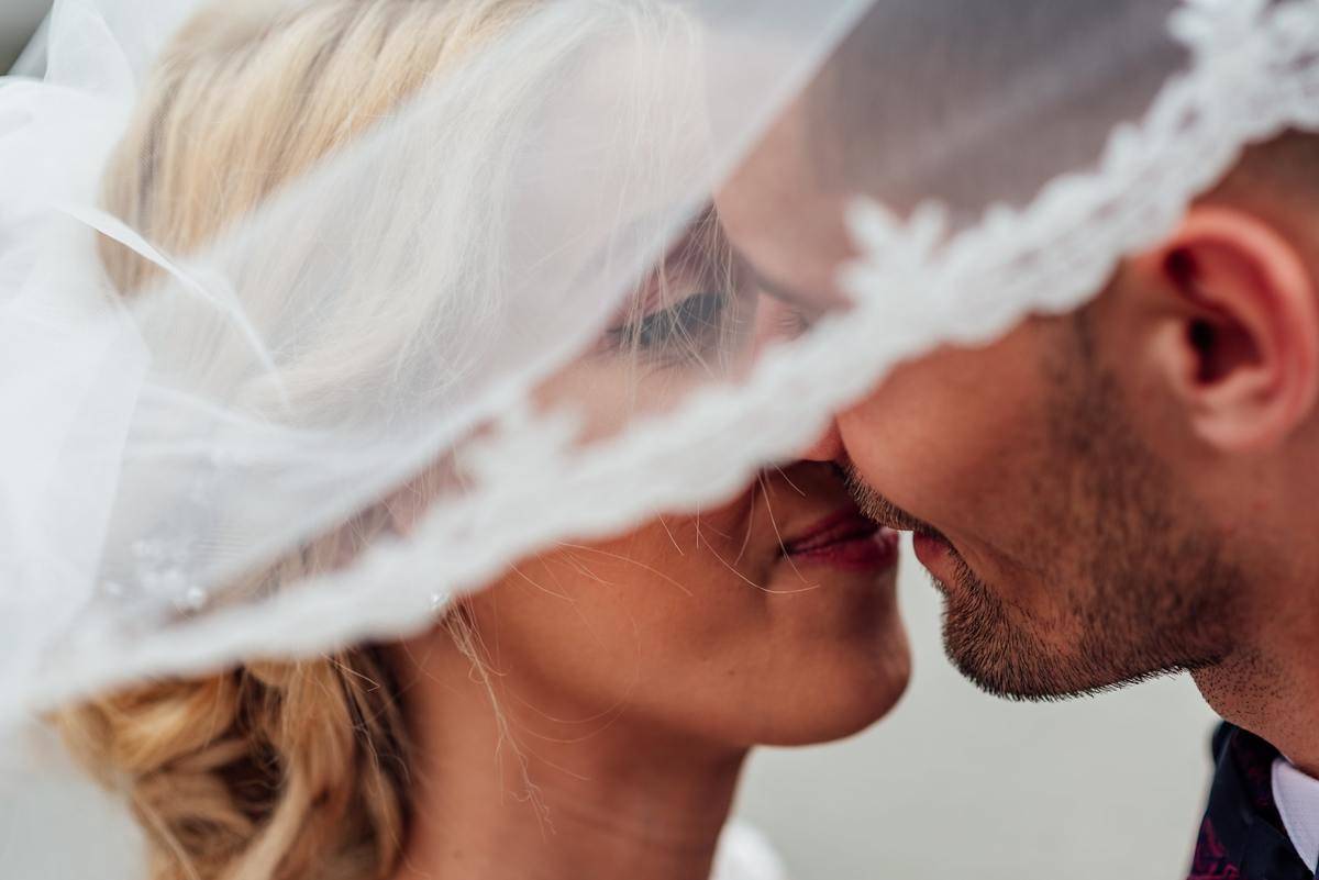 bride and groom under veil kiss