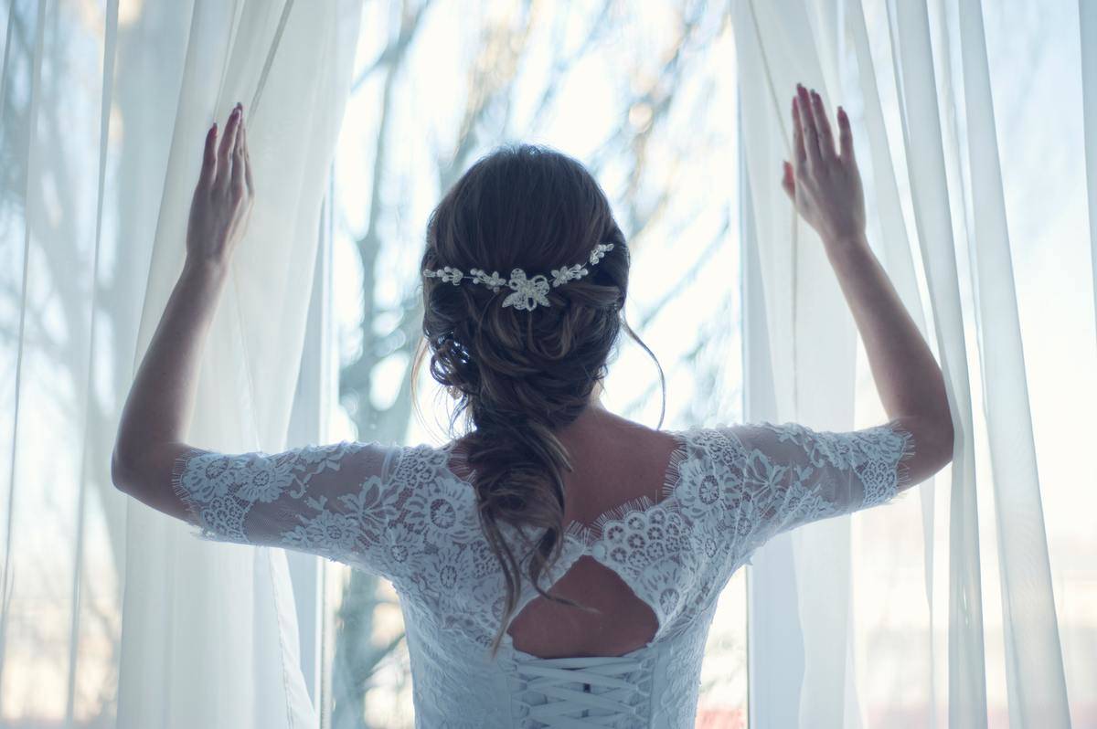 bride opening windows wearing wedding dress
