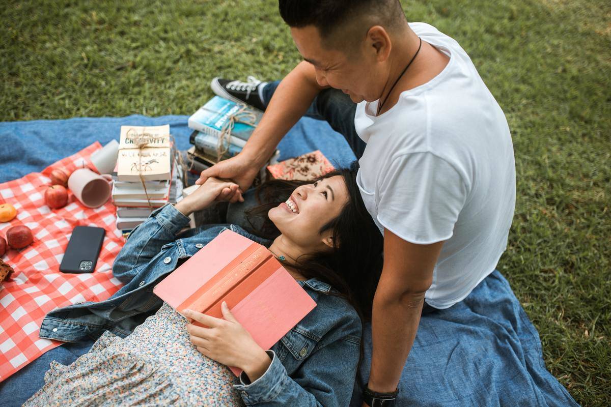 couple reading at picnic on blanket while cuddling