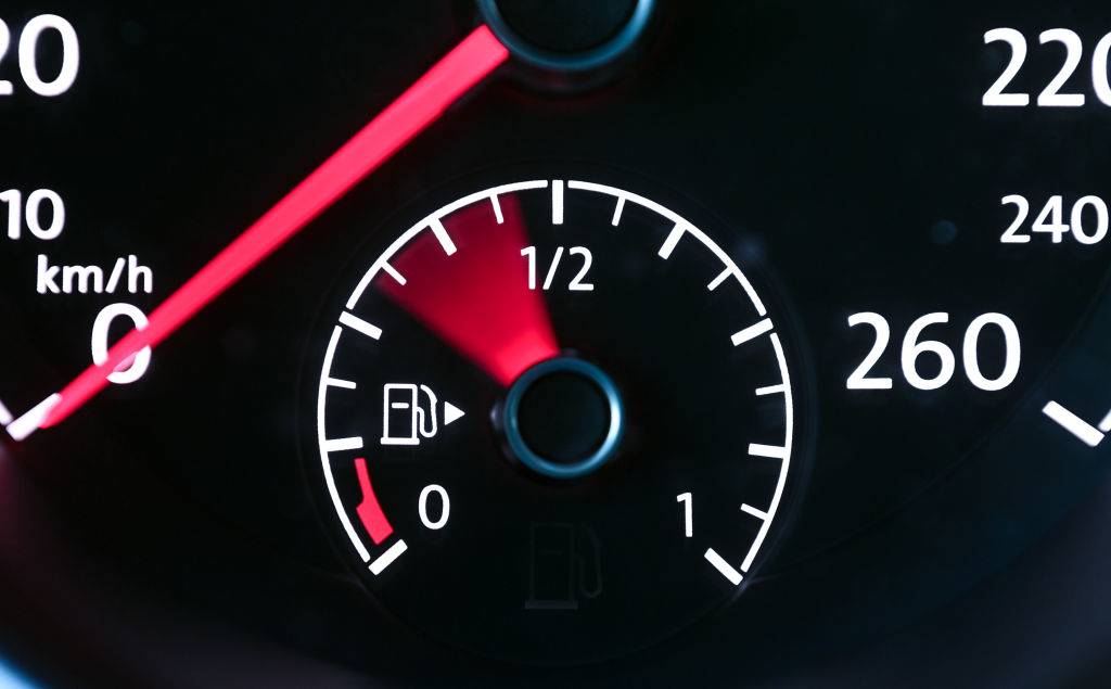 The pointer of the fuel gauge inside a car